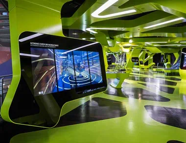 Blick in den Ausstellungsraum, im Fokus ist ein Exponat zum Thema nachhaltige Mobilität mit großem digitalen Bildschirm