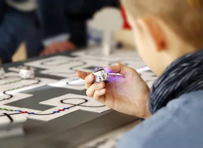 Ein Kind betrachtet einen kleinen Roboter