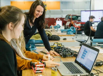 Zwei Mädchen bei einem Projekt in der Werkstatt, unterstützt durch eine Bildungsexpertin aus der Autostadt