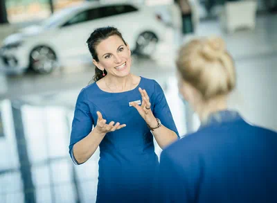 Eine Mitarbeiterin der Autostadt im Gespräch mit einer anderen Person