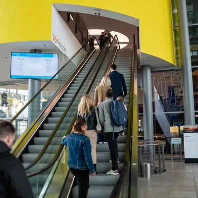 Several people stand on an escalator in the Autostadt piazza