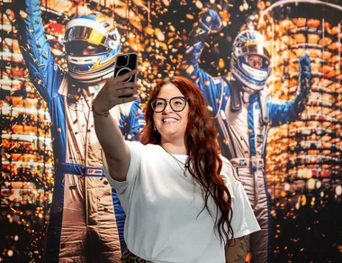 Eine Frau macht ein Selfie vor einer Social Wall